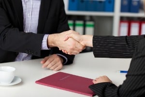 Businesspeople Shaking Hands At Office Desk